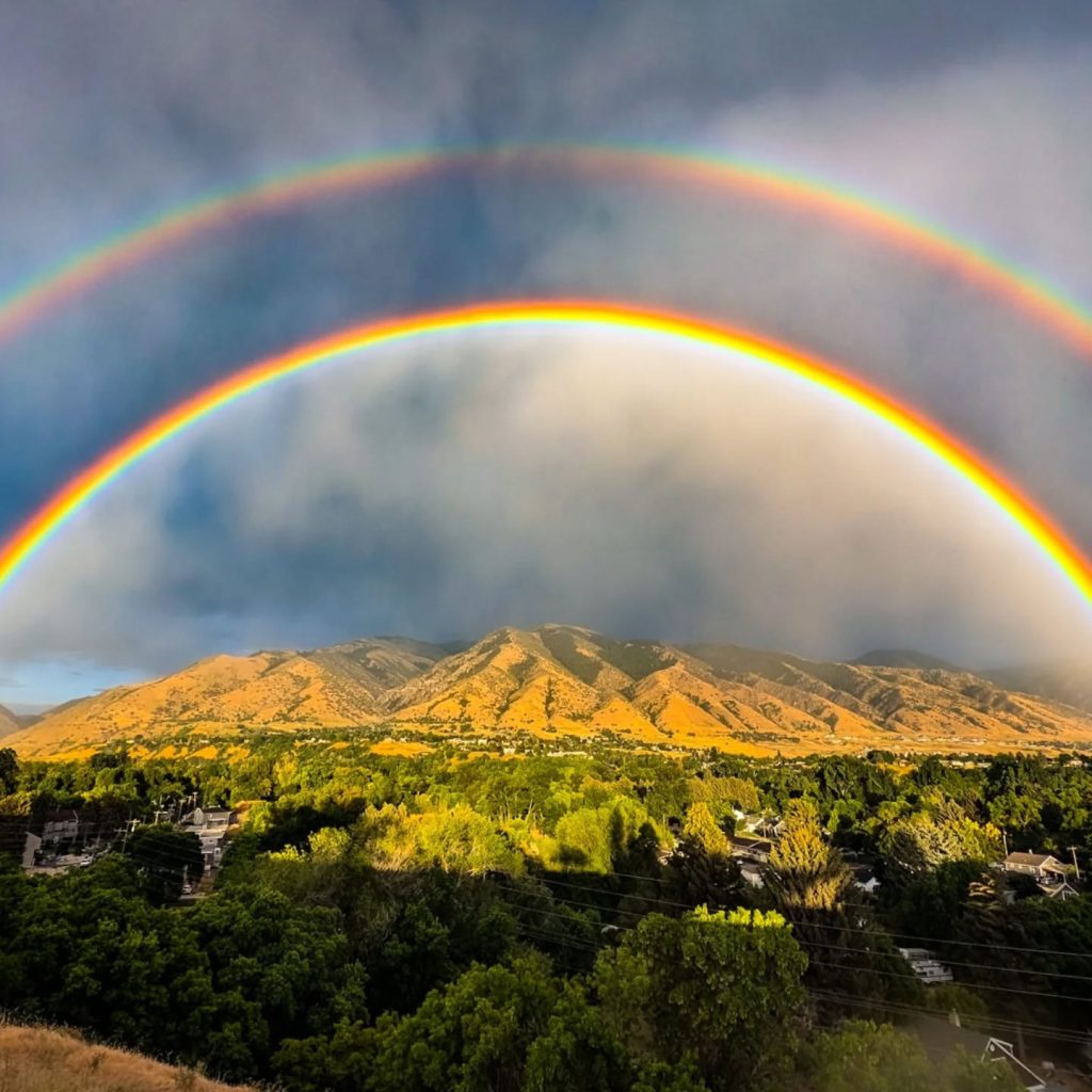 A double rainbow arcs over the Island in Logan, Utah – and the mountains to the east of it.